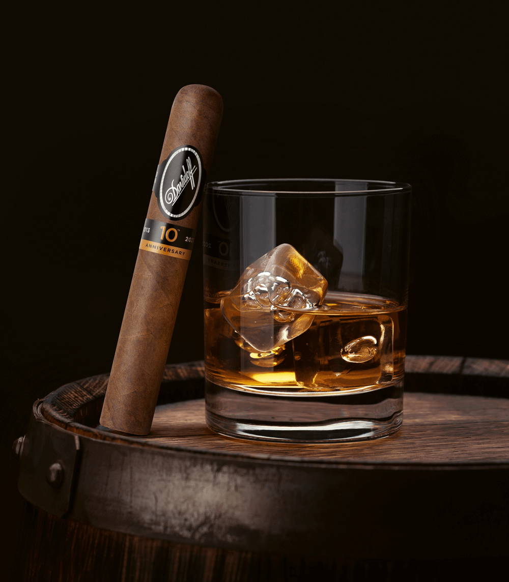 Die Davidoff Nicaragua 10th Anniversary Limited Edition Gran Toro Zigarre, die gegen ein Glas mit Rum lehnt.