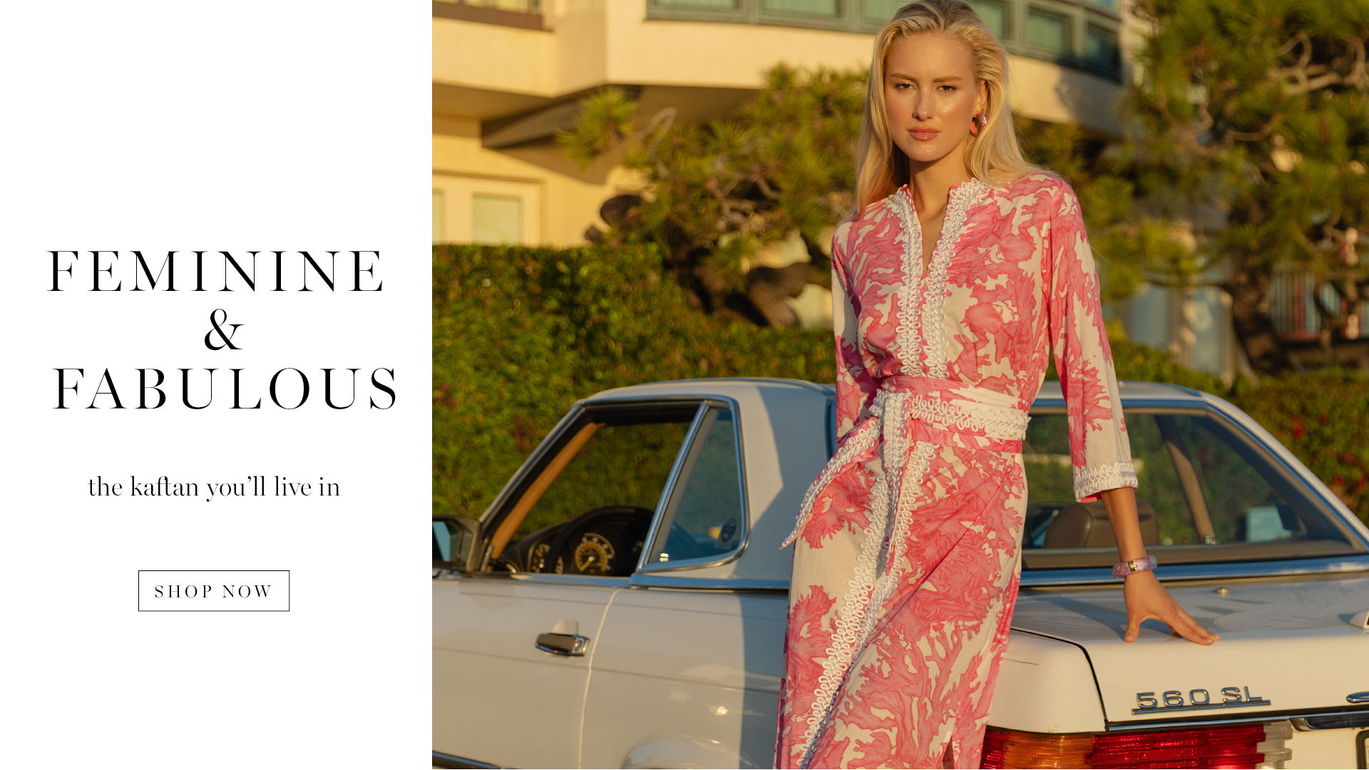A woman in a floral dress stands by a vintage car.