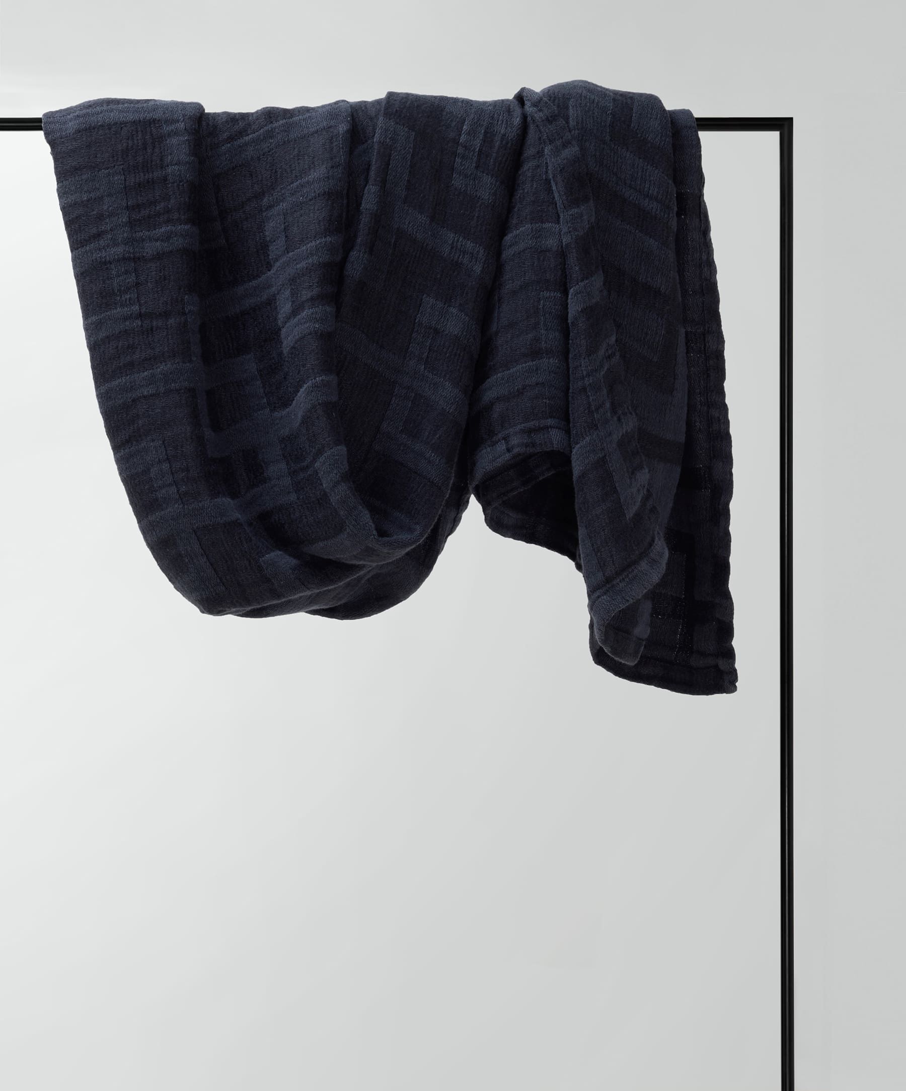 Dark blue towel draped over a black metal rod on a light gray background