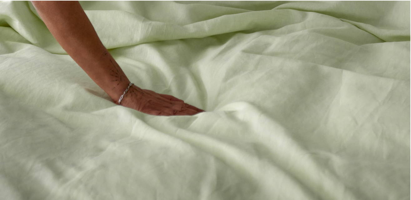 Eine Hand fährt über Bettwäsche
