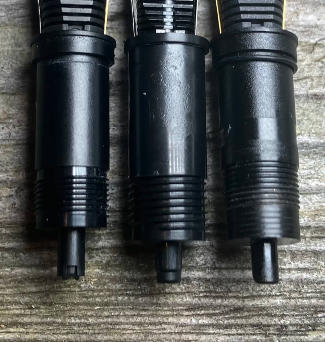 A closeup photo of the different thread standards on different nibs, on a wooden surface