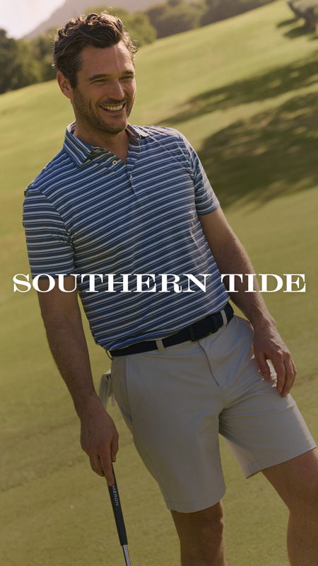 Smiling man in golf attire standing on a green field.