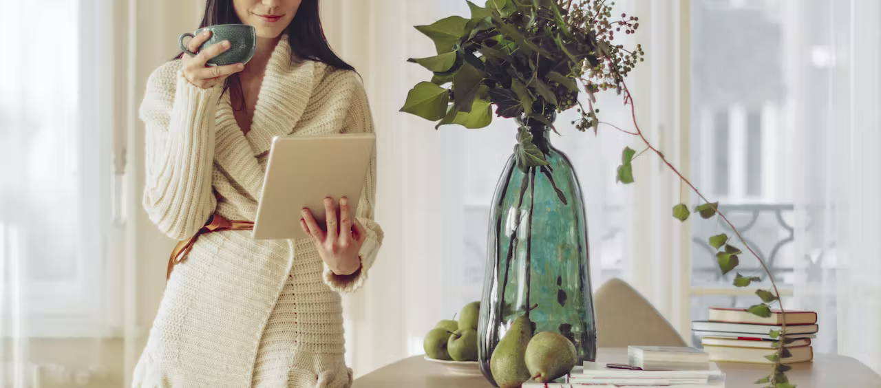 Woman drinking coffee looking at a tablet computer