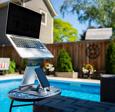 Laptop Tower II stand with smartphone and computer on table poolside.