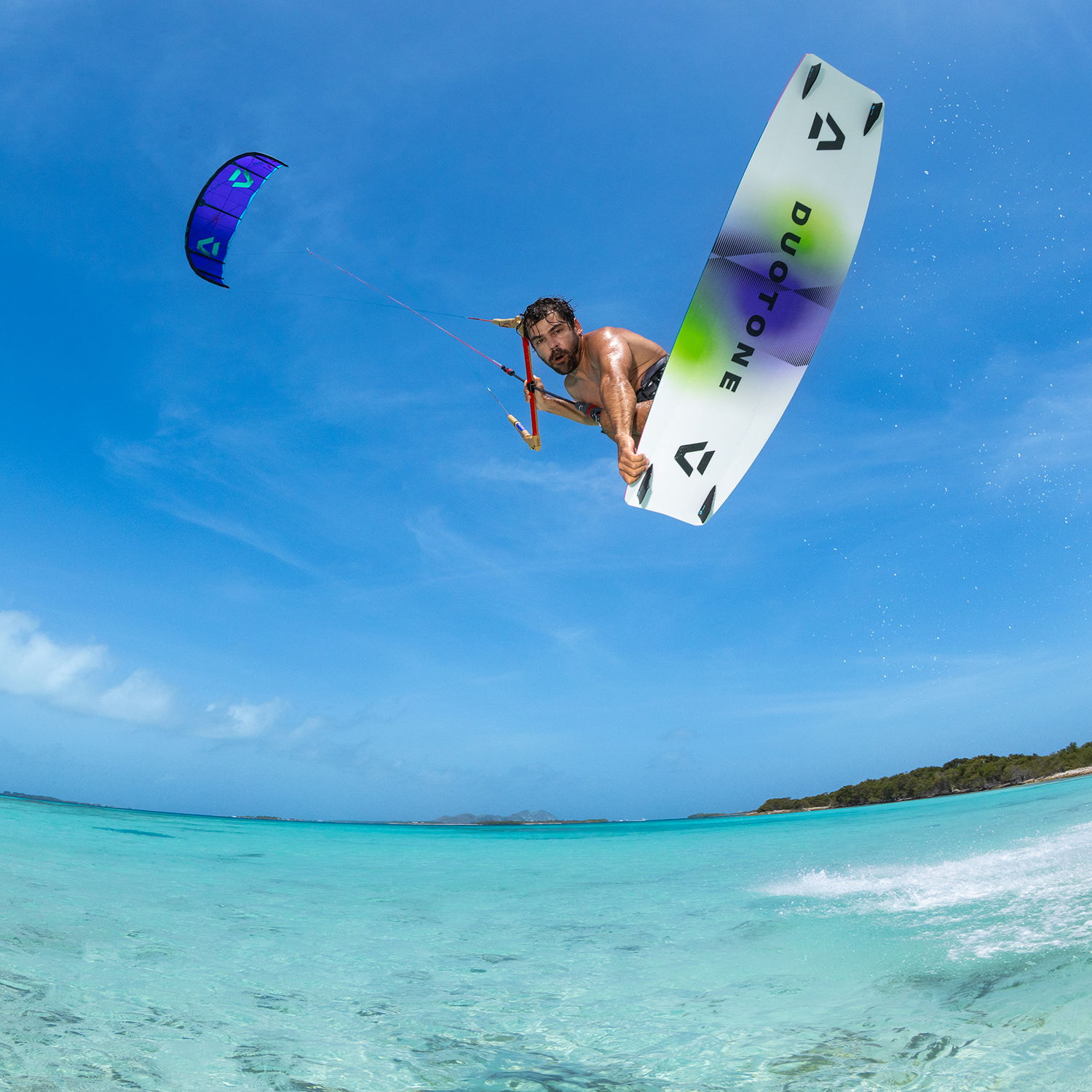 Une personne faisant du kitesurf au-dessus d'une eau bleue cristalline.