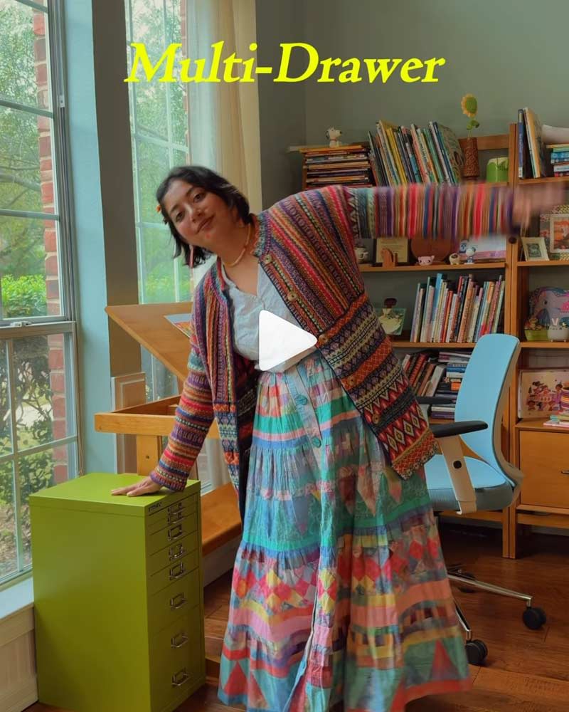 Person in colorful dress near a multi-drawer storage unit in a bright room.