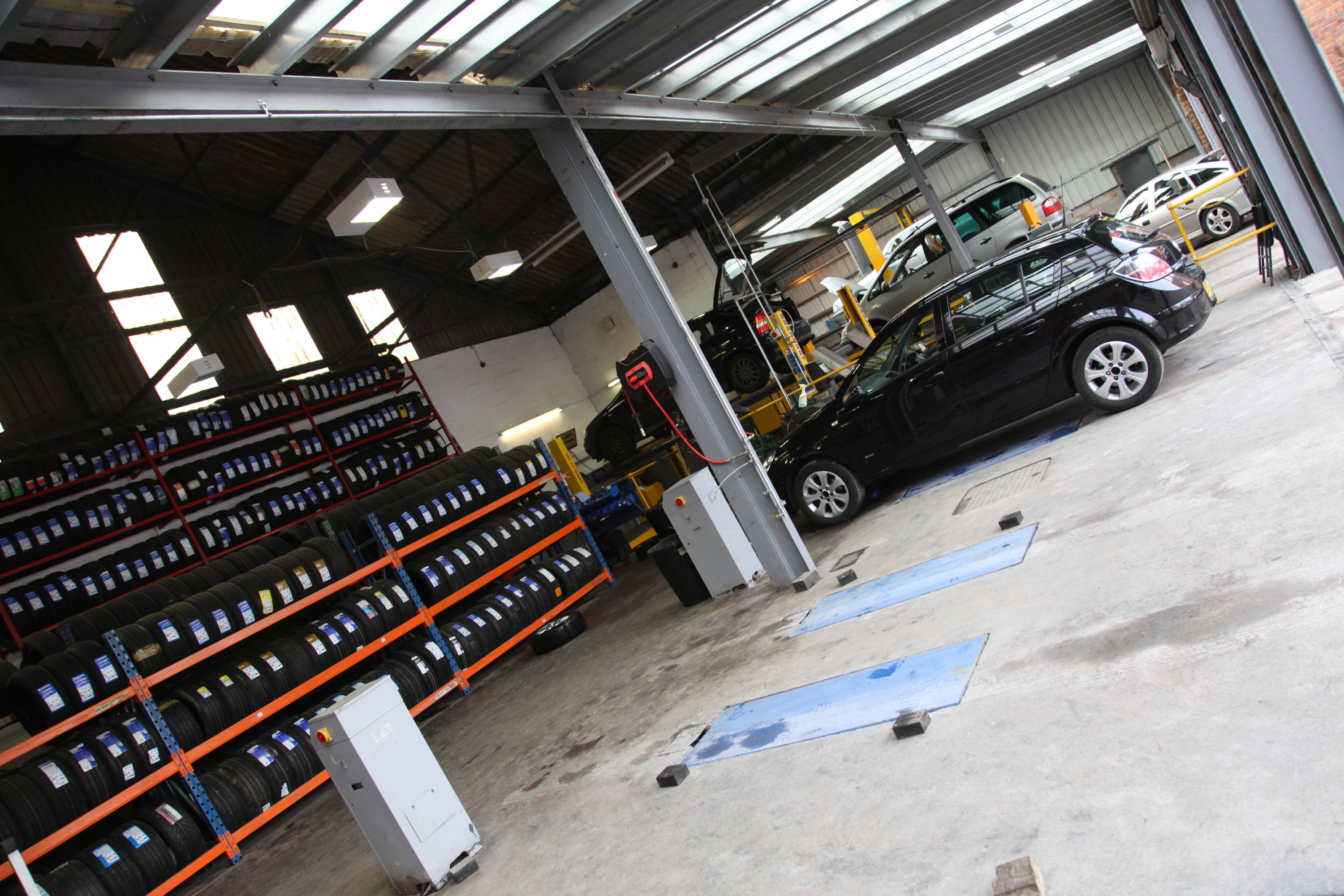 Inside Wednesbury car garage with rows of tyres and car parked 