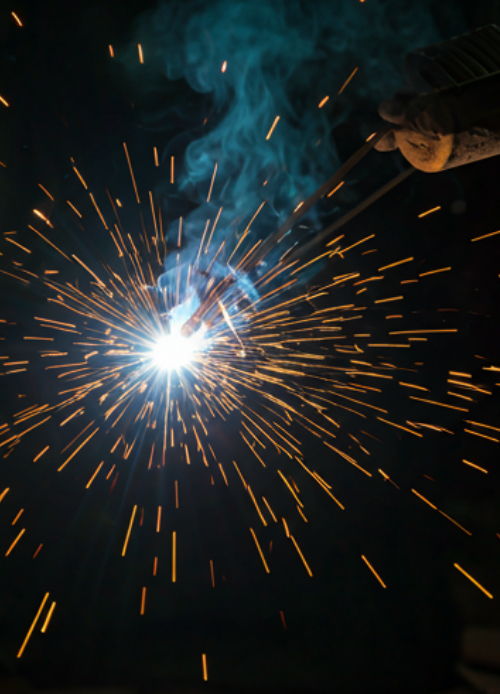 Bright sparks and smoke from a welding process against a dark background.