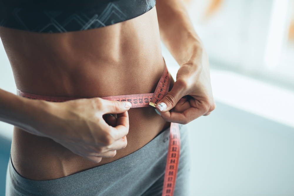healthy-vegan-woman-measuring-her-waist