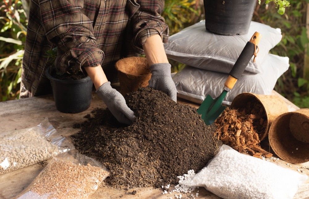A person mixes potting soil ingredients preparing to plant their potted plants and flowers