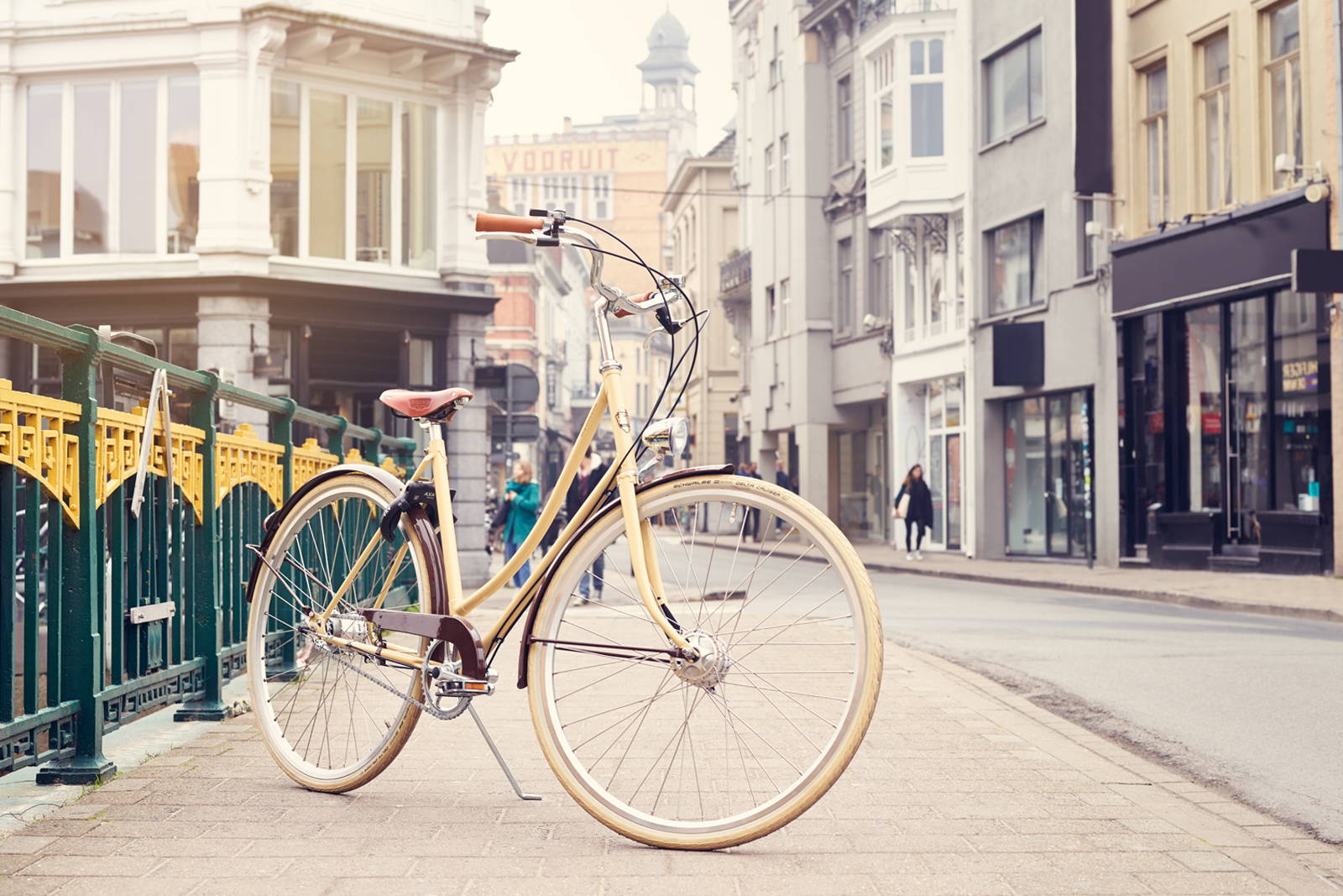 A cream Achielle Babette with brown fenders sits on a city street in Europe.