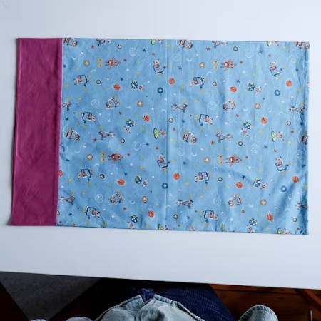 finished pillowcase with a magenta band and blue fabric with robot drawings