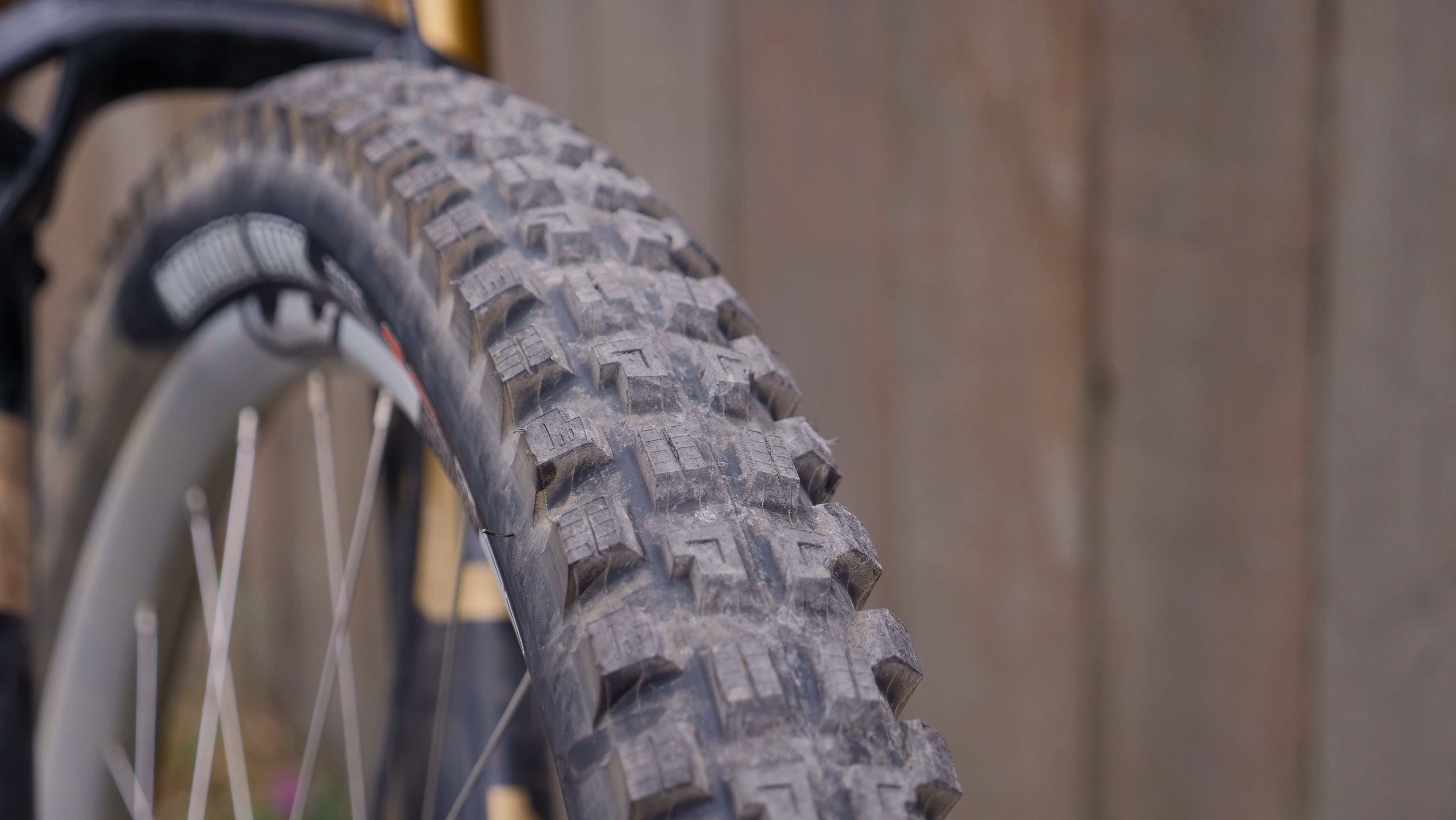 Close-up of a mountain bike tire against a wooden background.