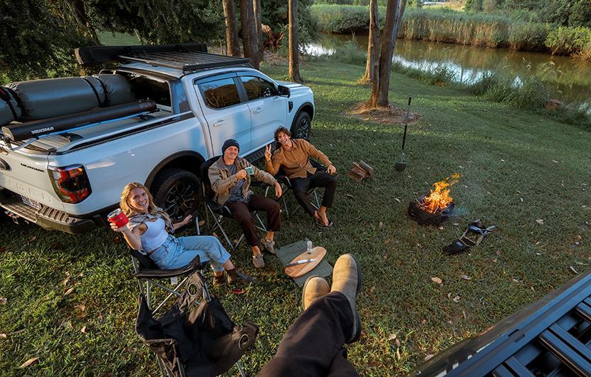People camping and sitting outdoors with a ute with roof rack platform 