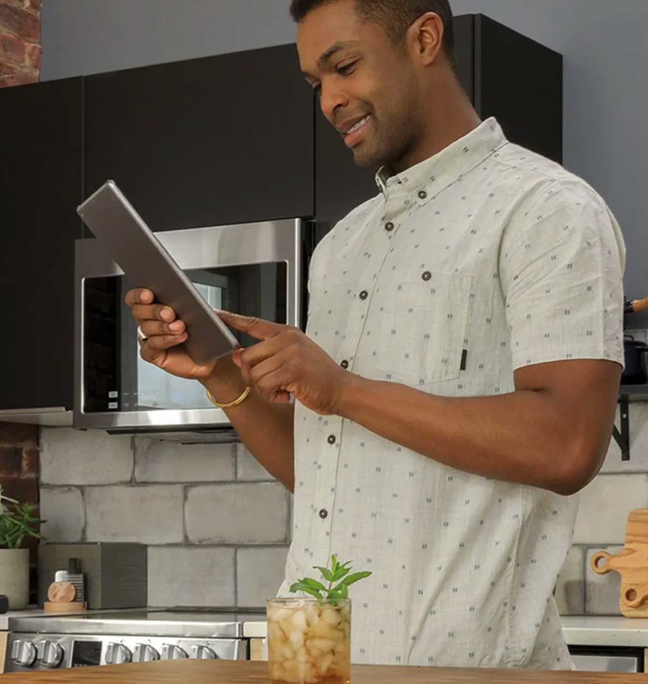 Young african american man checks his iPad while in his kitchen.a