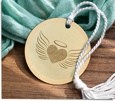 brass keepsake Christmas ornament engraved with a fingerprint in the shape of a heart with angel wings and halo