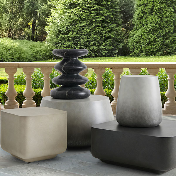 Various decorative stone planters on a patio with green landscaping.