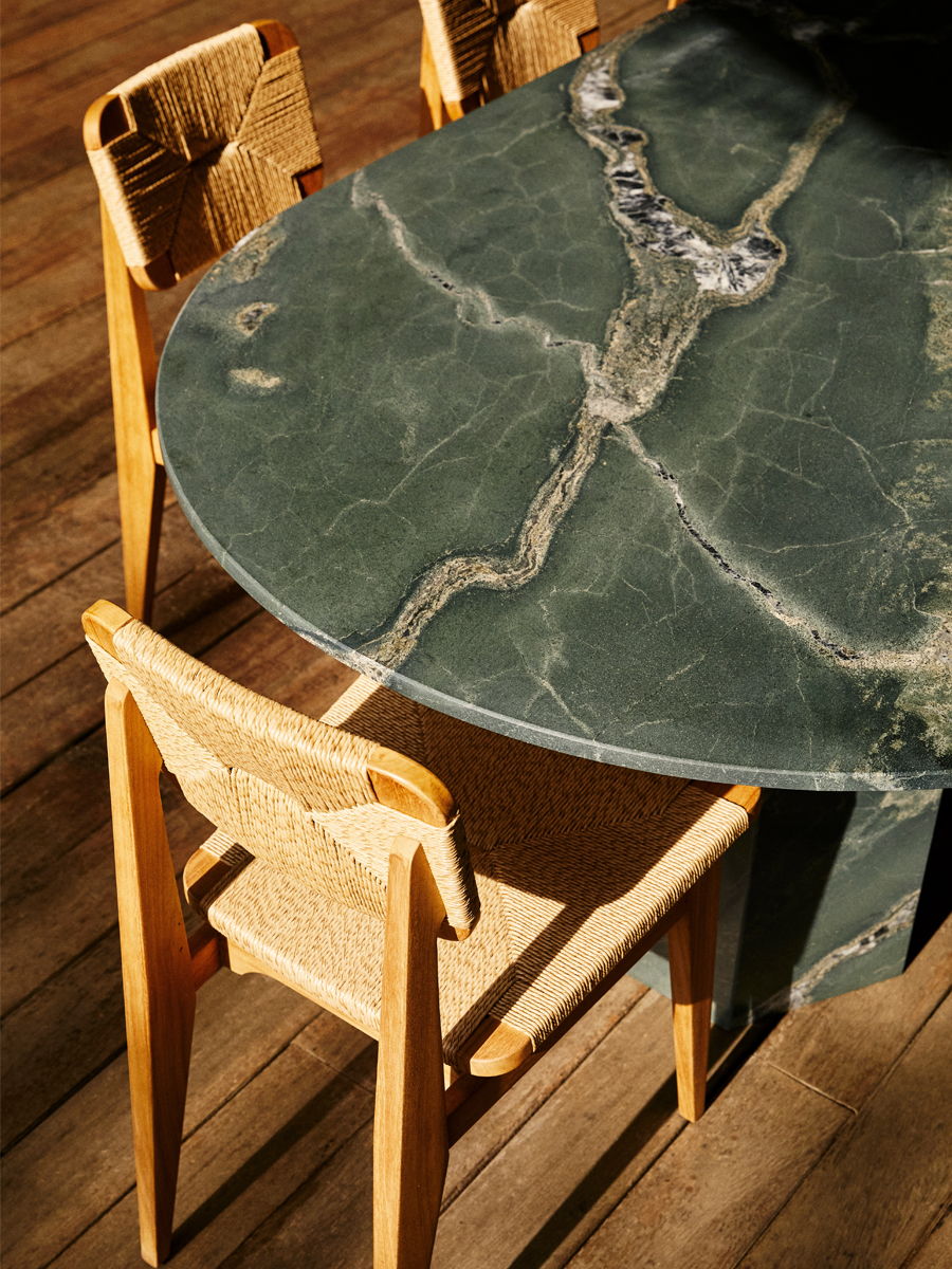 A round green marble table with wooden chairs around it.