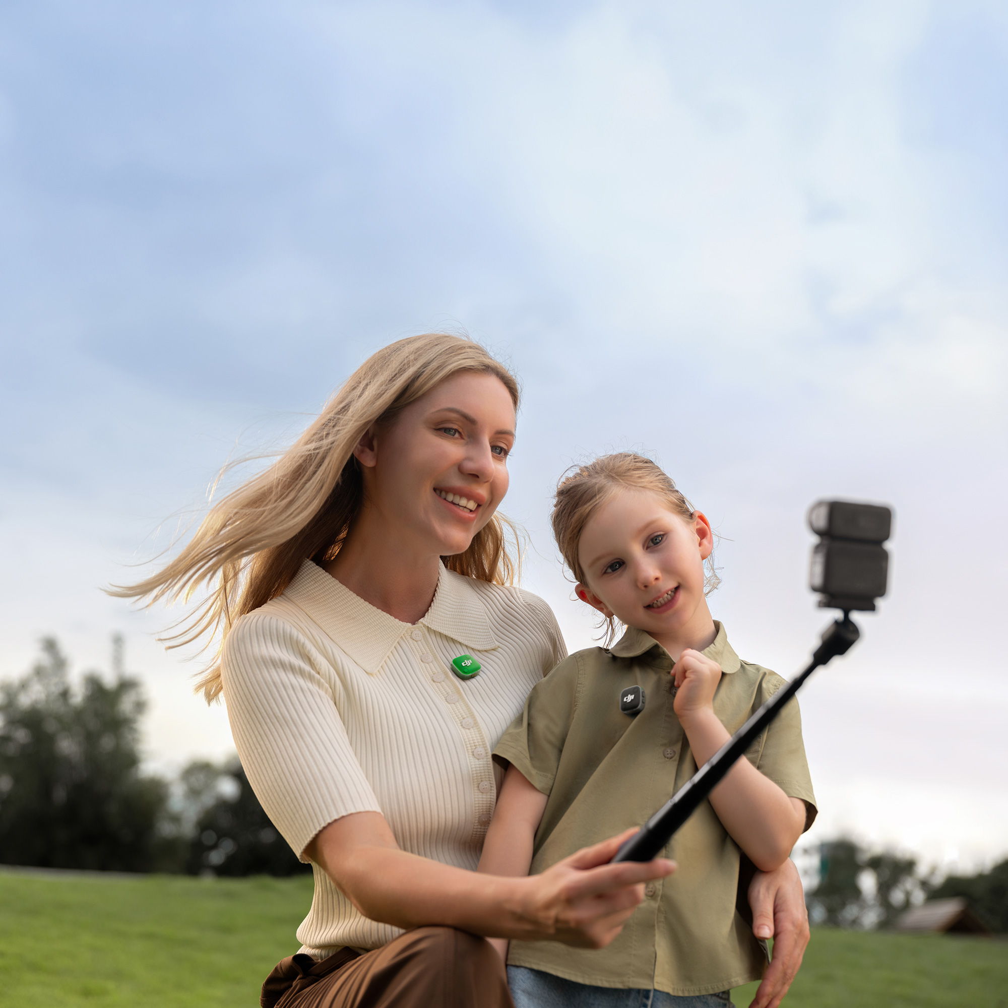 A woman and child taking a selfie with a DJI Osmo Nano while recording audio with DJI Mic Mini 2 in a park.