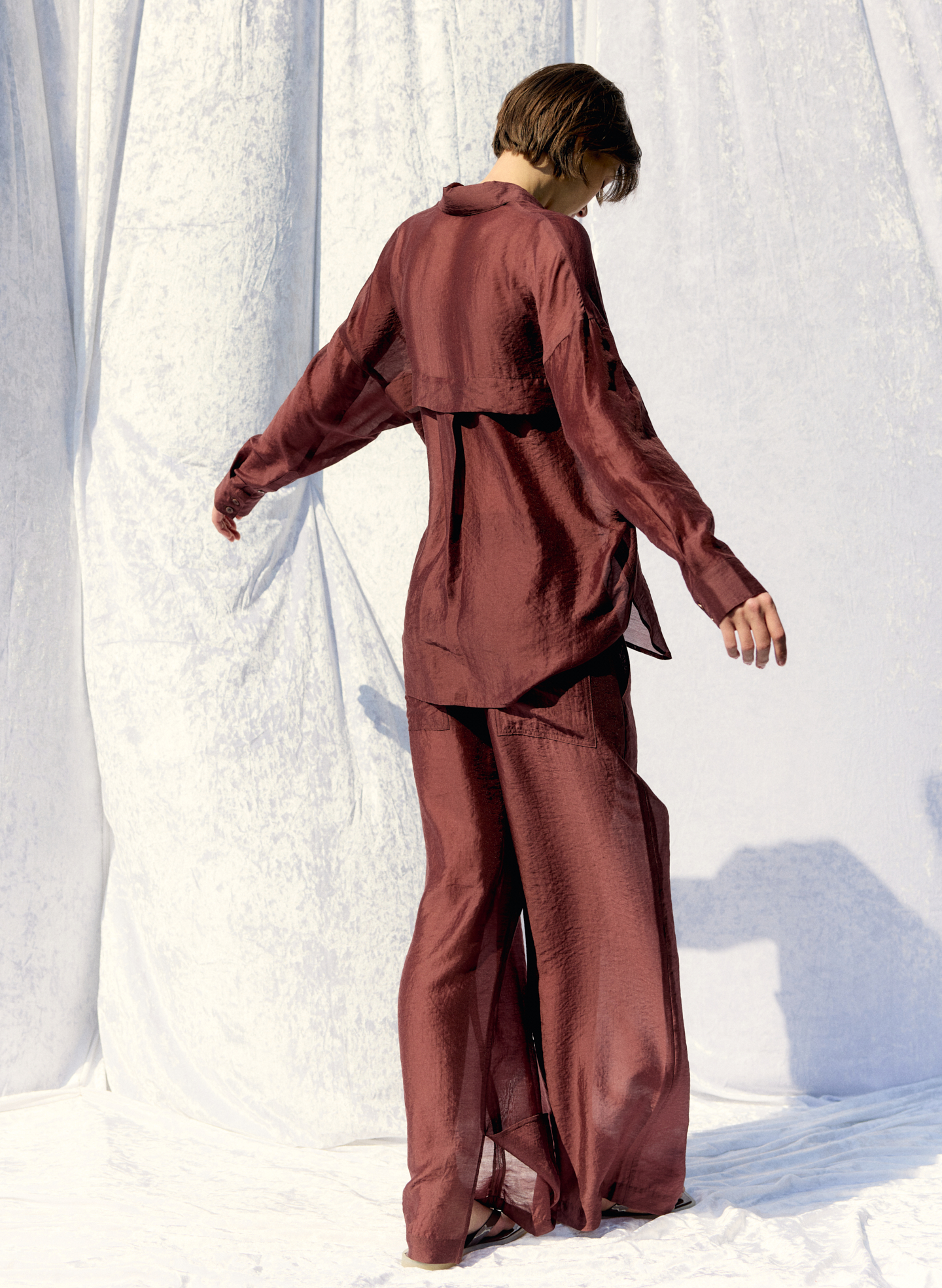 A person wearing a maroon outfit, facing away, against a light background.