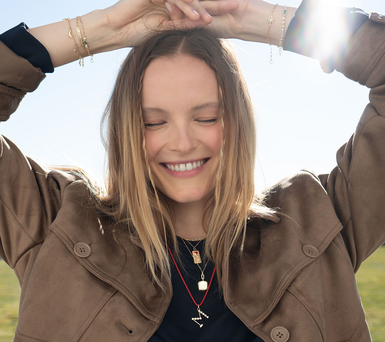 Smiling woman with closed eyes, enjoying sunlight outdoors.