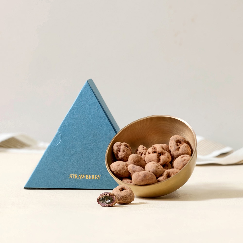 Bowl of snacks beside a blue triangular box on a light background.