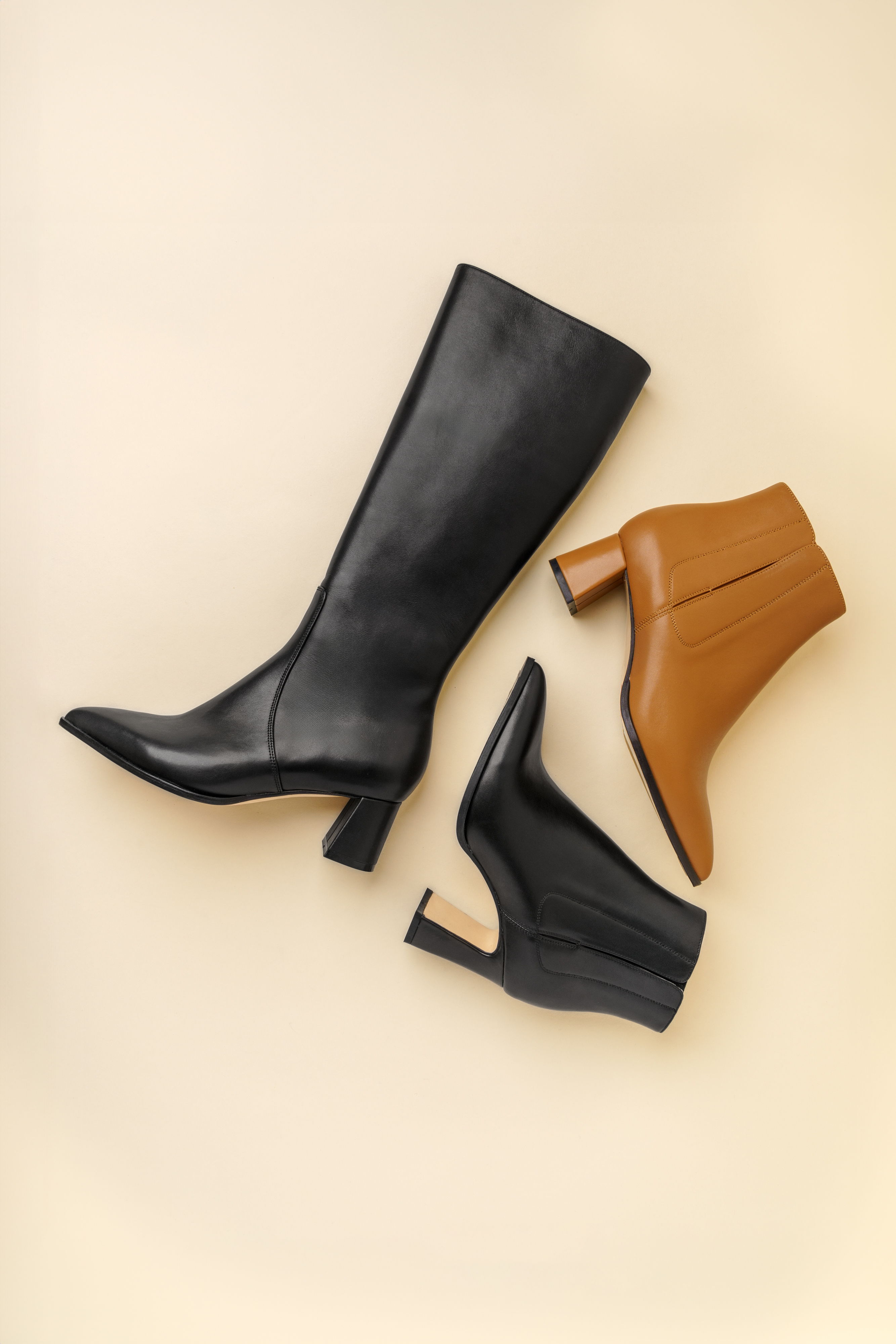 Three stylish boots on a beige background: black knee-high and brown ankle boots.