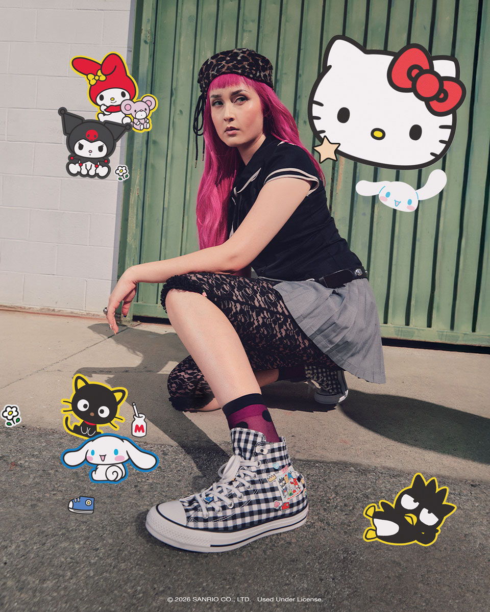 A person with pink hair poses with Hello Kitty graphics around them.