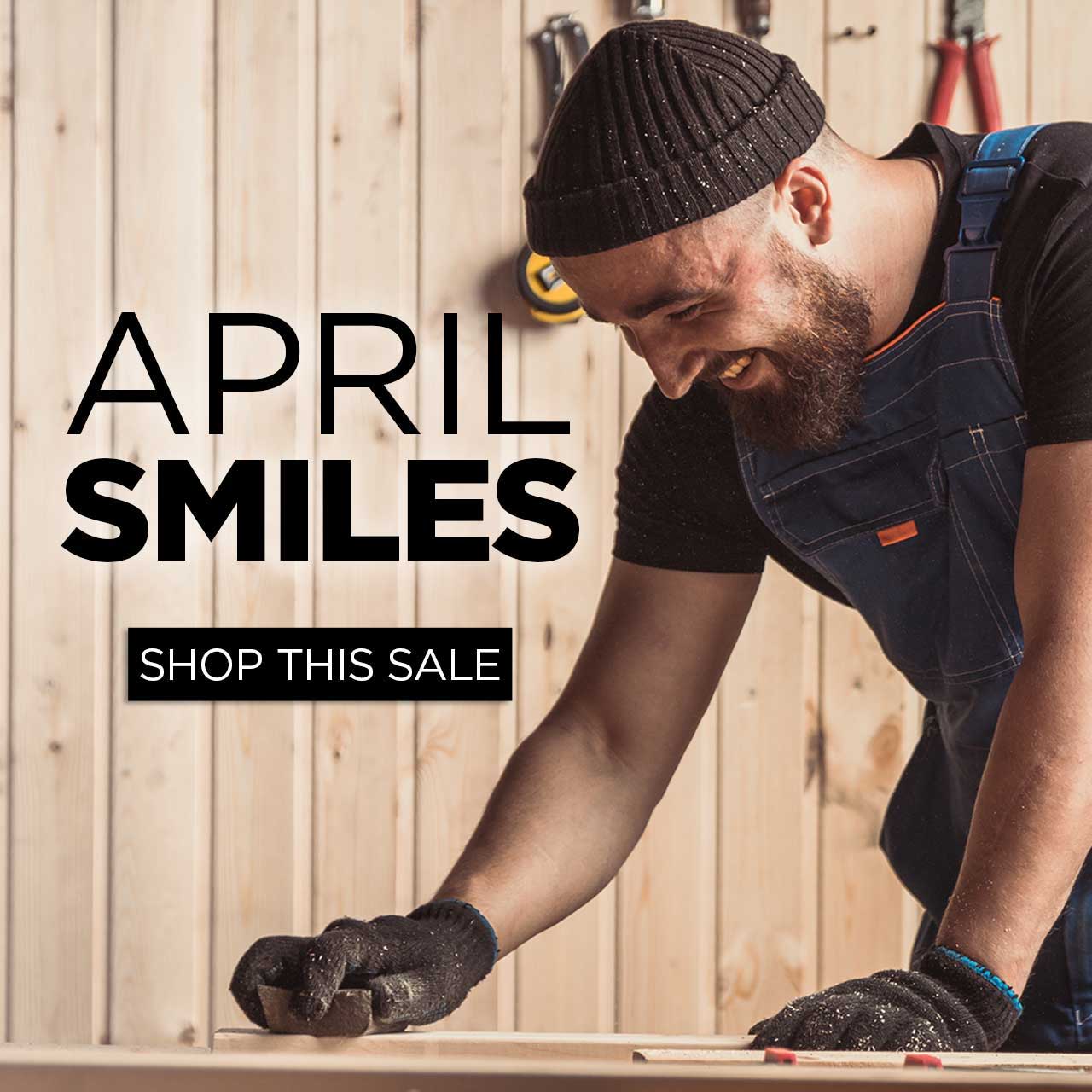 Man smiling while working with wood, promoting April sale.