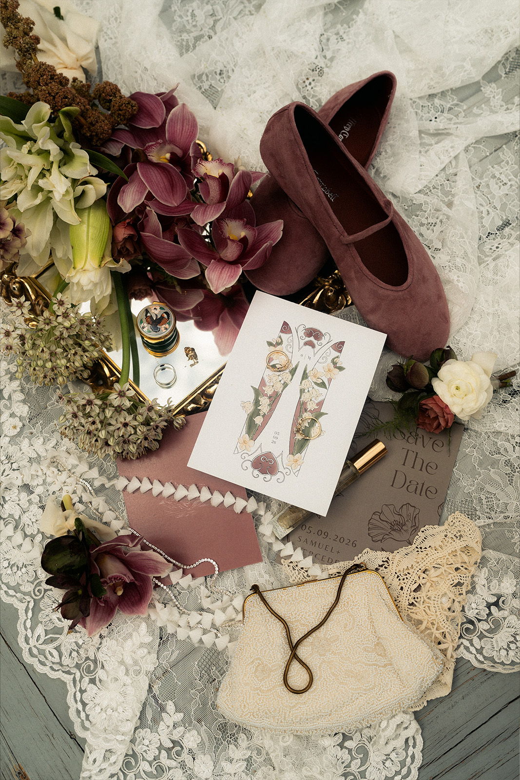 Flat lay of shoes, flowers, and decorative items on lace fabric.