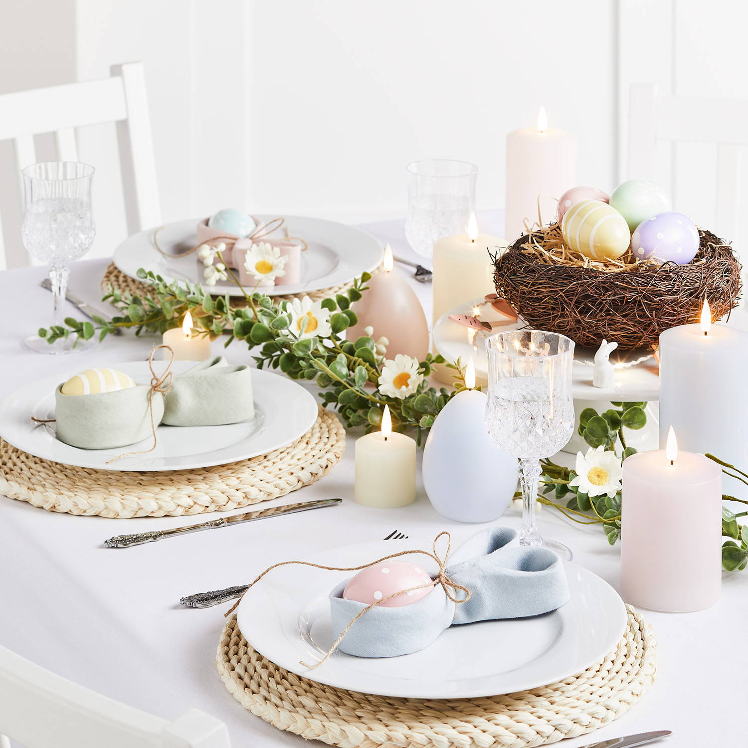 une table de pâques merveilleusement décorée par des bougies et oeufs de pâques de couleur pastel. 