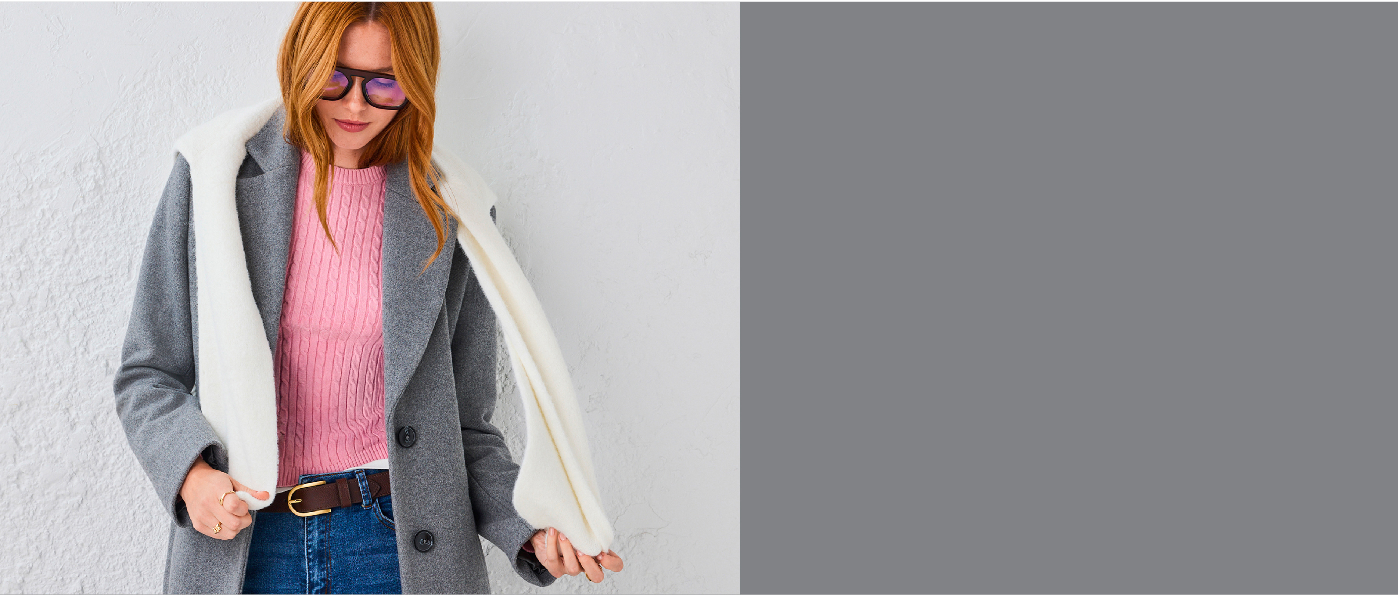 Woman with red hair wearing a gray coat and pink shirt.