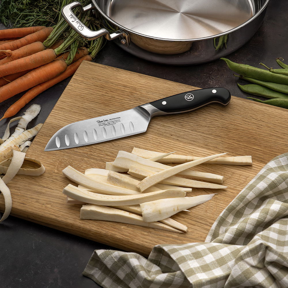 Chopped vegetables and the 14cm Professional Santoku Knife on a wooden cutting board with kitchenware.