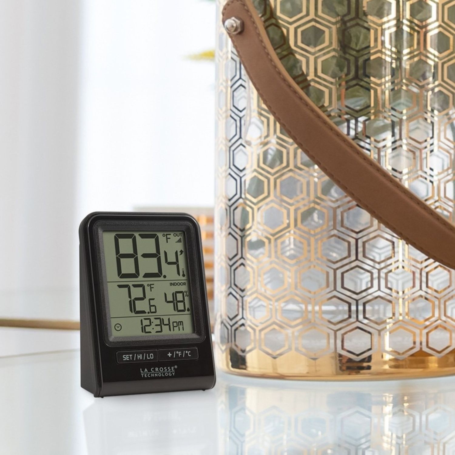 Digital thermometer next to a decorative glass container and strap.