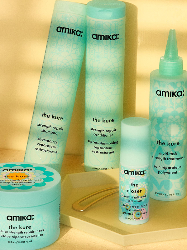 Amika hair care products displayed on a yellow background.