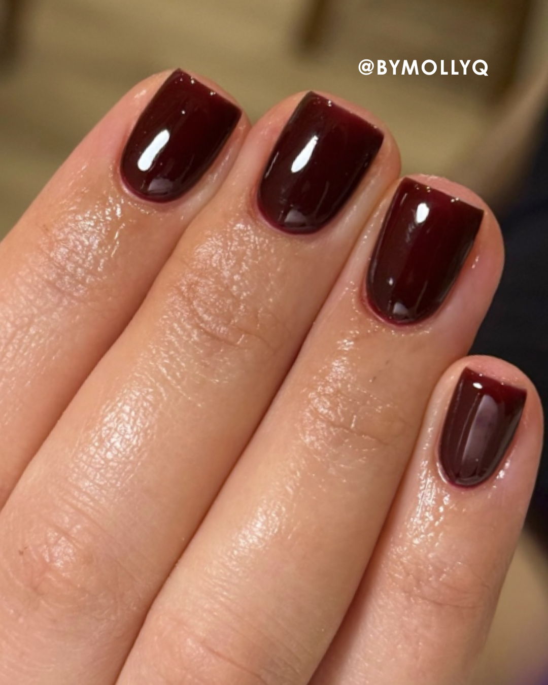 A hand with dark red glossy nail polish.
