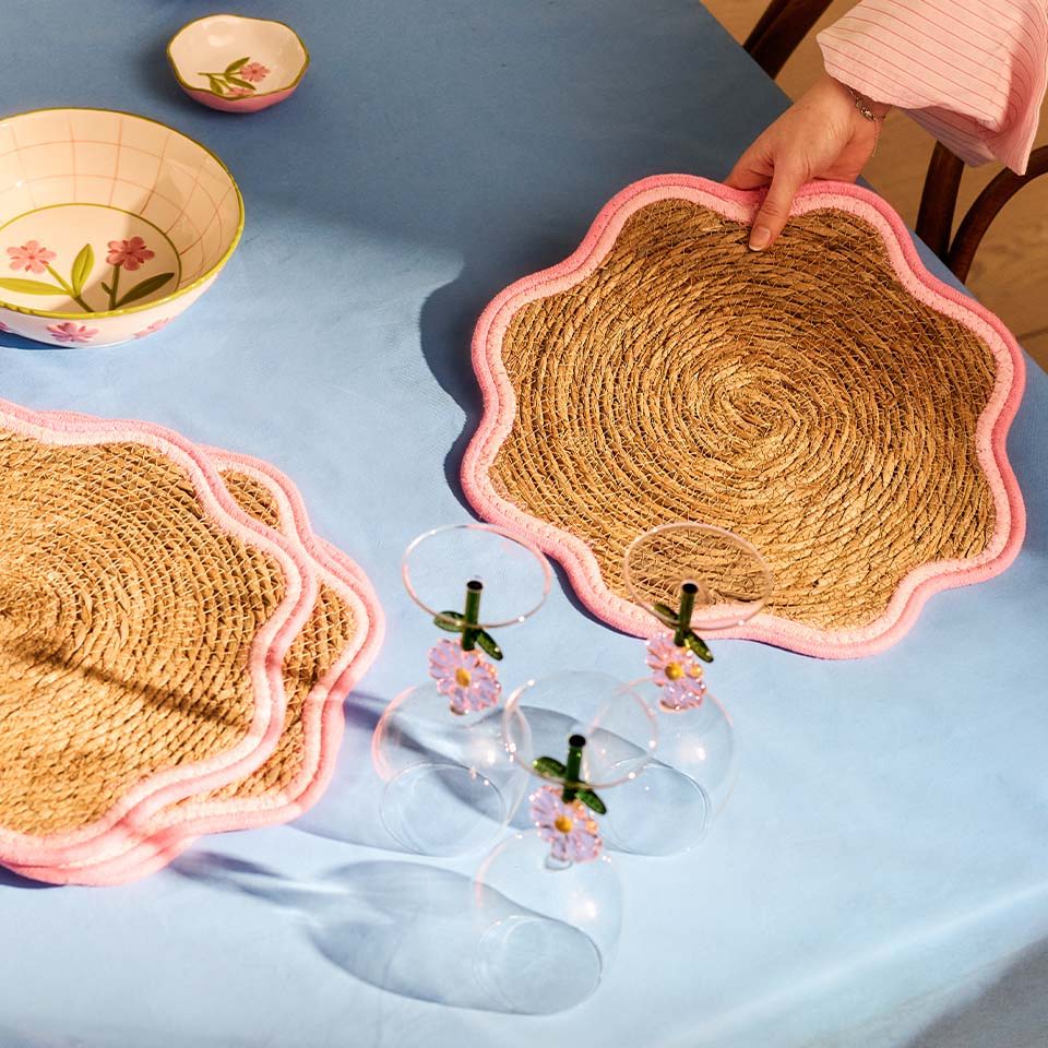 Colorful woven placemats and glass cups on a blue table.