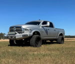 Front quarter view of lifted silver Ram 2500 Heavy Duty with LED bumper and off-road tires in field