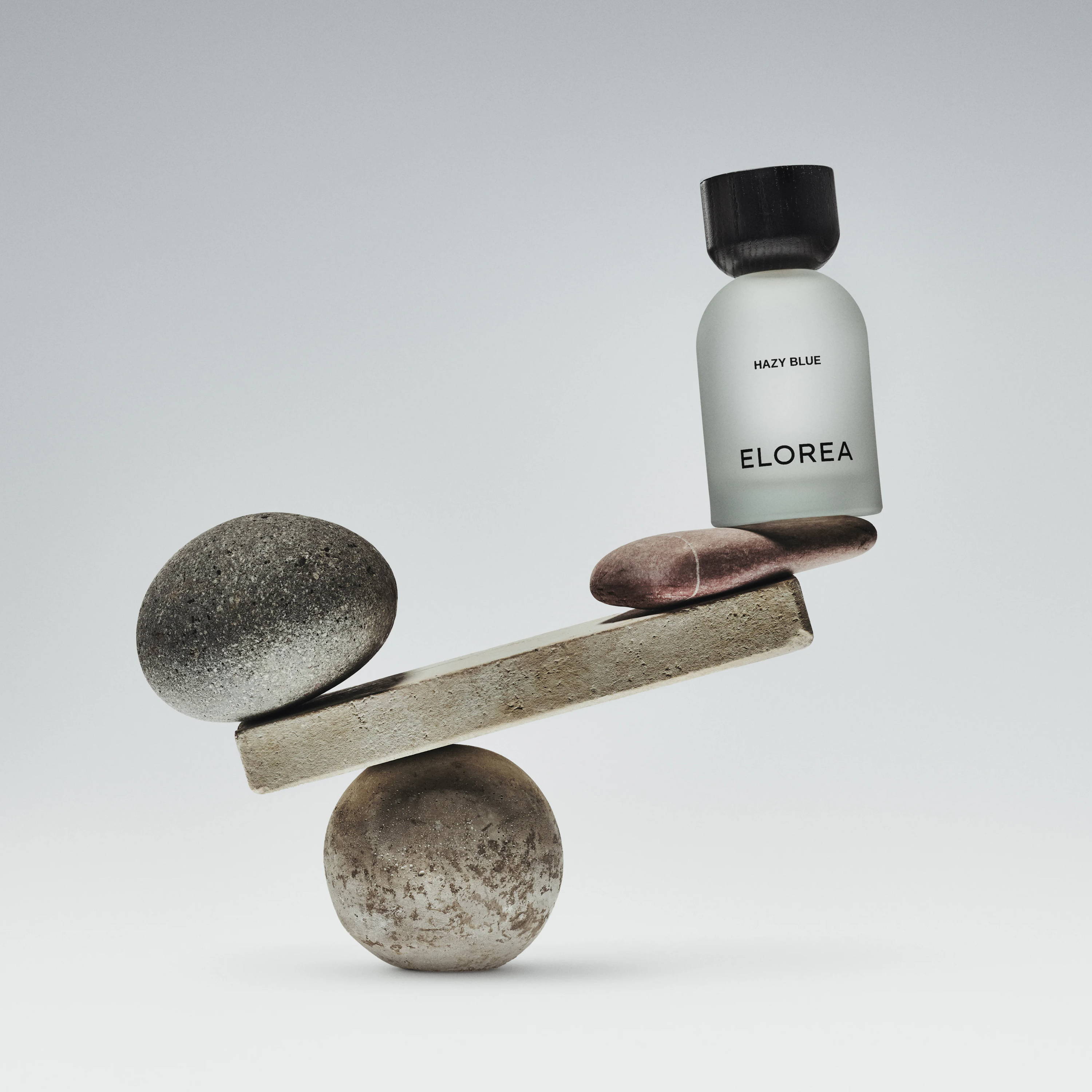 A bottle of perfume balanced on stones.