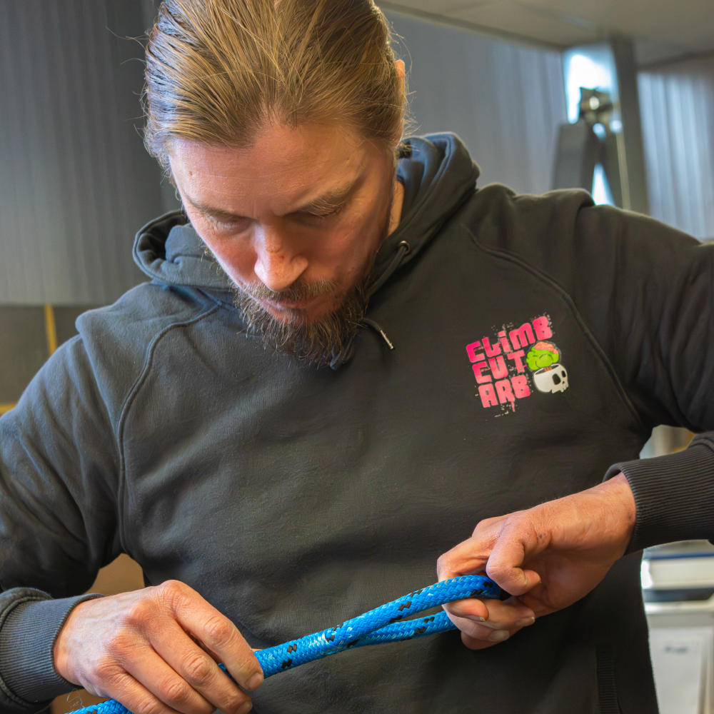 Person inspecting or handling a blue rope indoors.