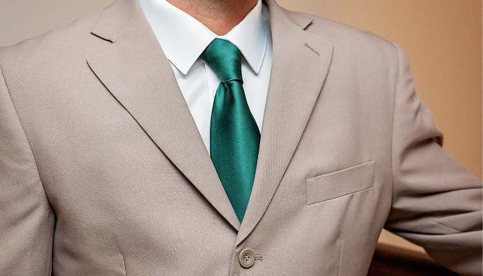 Man wearing tan suit and hunter green tie