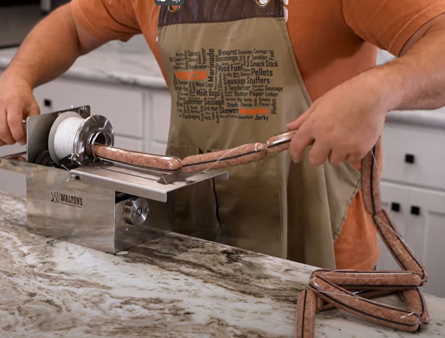 Person using a sausage maker in a kitchen setting.
