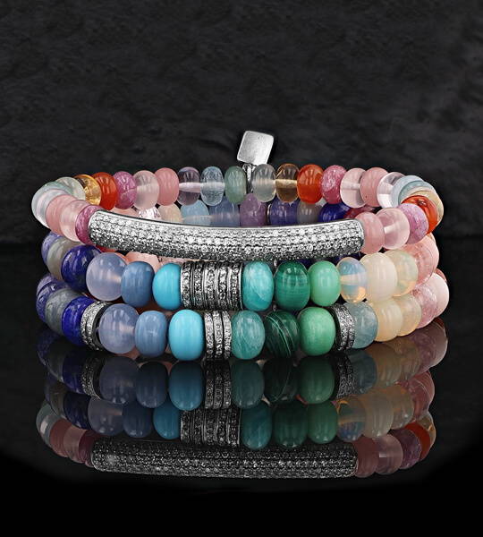 A colorful rainbow stack of gemstone bead and diamond bracelets for women.