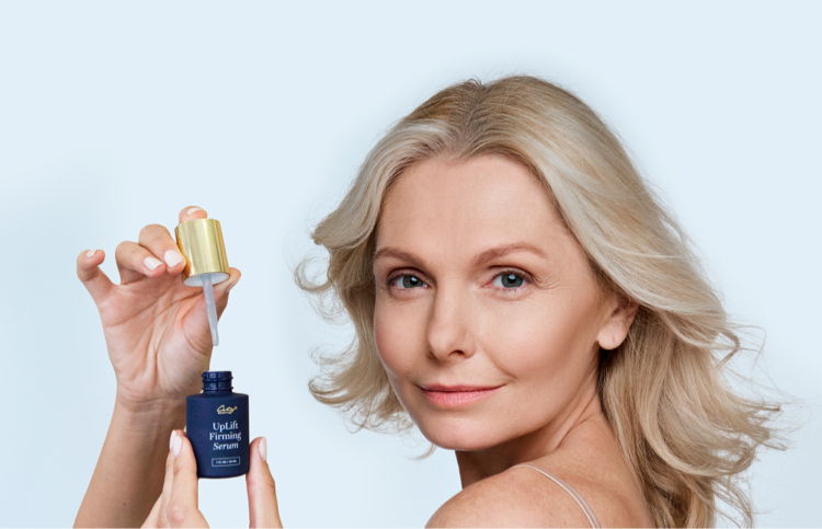 Woman holding a serum bottle with a dropper, smiling at the camera.