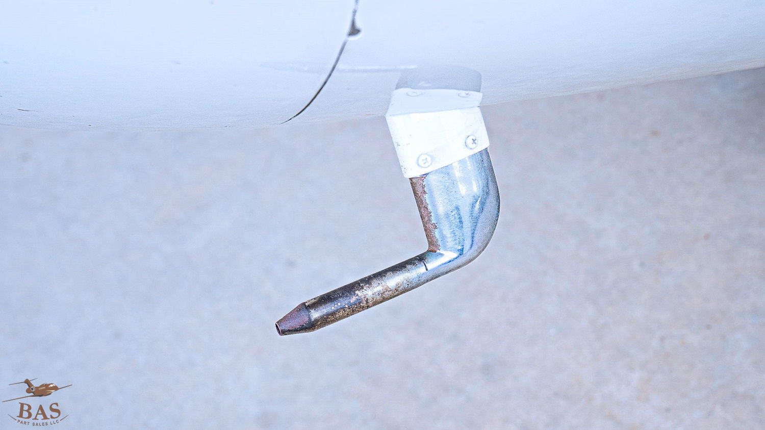 Metal pipe extending from a surface, with a white rectangular attachment.