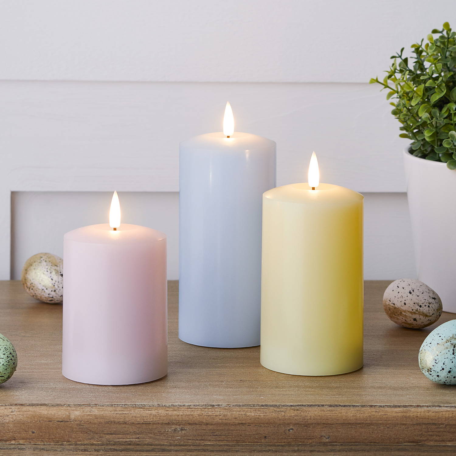 Blue, pink and yellow LED pillar candles on an Easter side table.