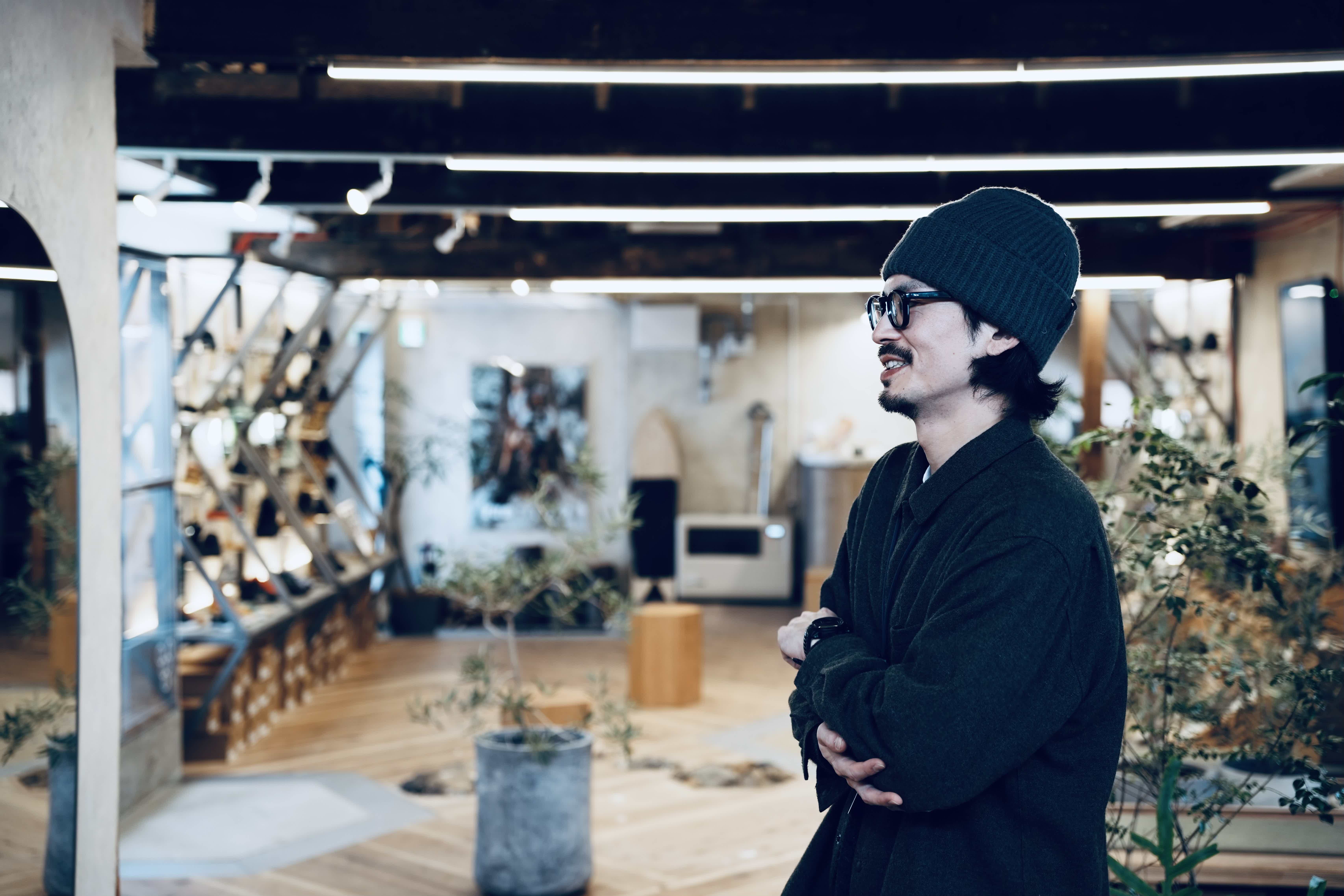 A person wearing a beanie stands in an artistic indoor space.