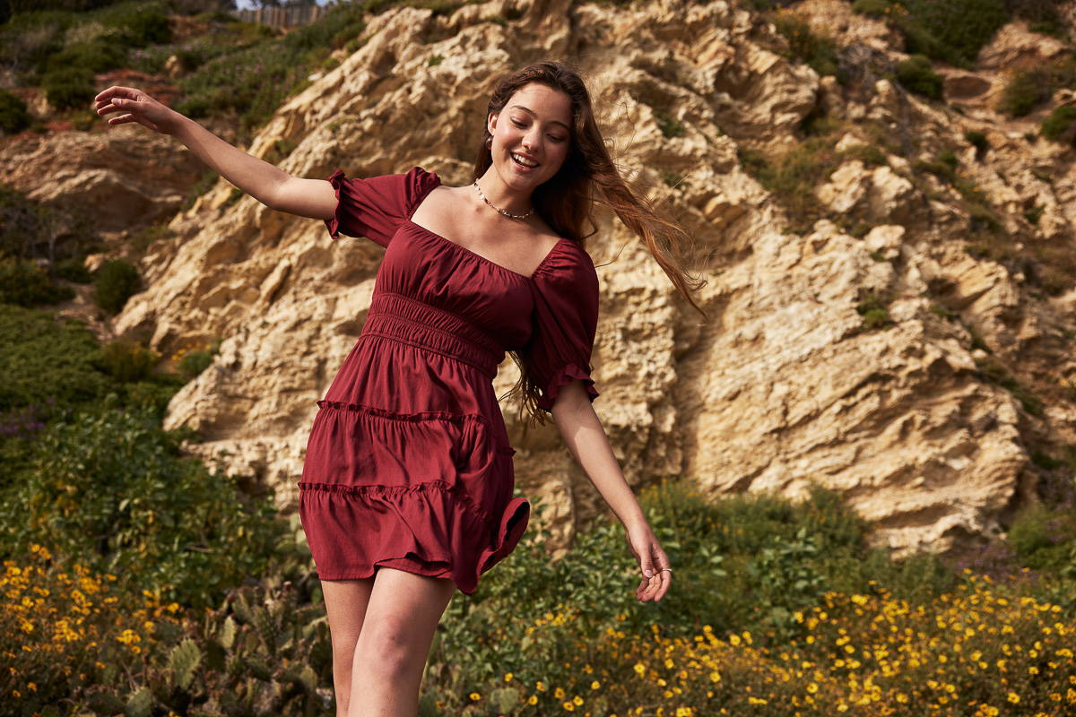 Trixxi sun-kissed summer, girls walking in floral mountain field in maroon red tier ruffle dress.
