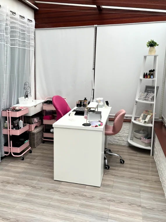 A modern, tidy workspace with a white desk and pink chairs.