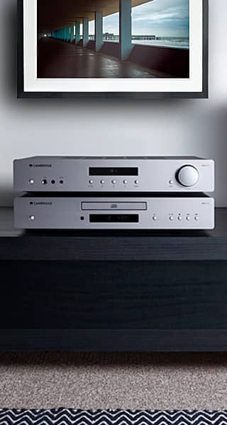 Two silver audio components stacked on a dark wooden surface.
